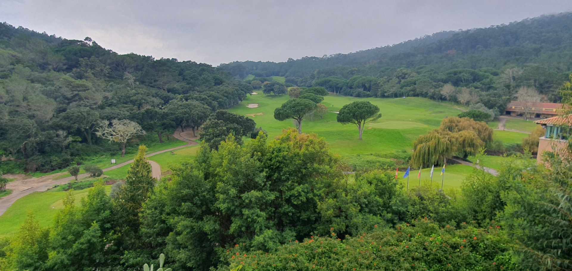 Weitläufiger grüner Golfplatz am Penha Longa Resort unter leicht bewölktem Himmel in der Hügellandschaft von Sintra.