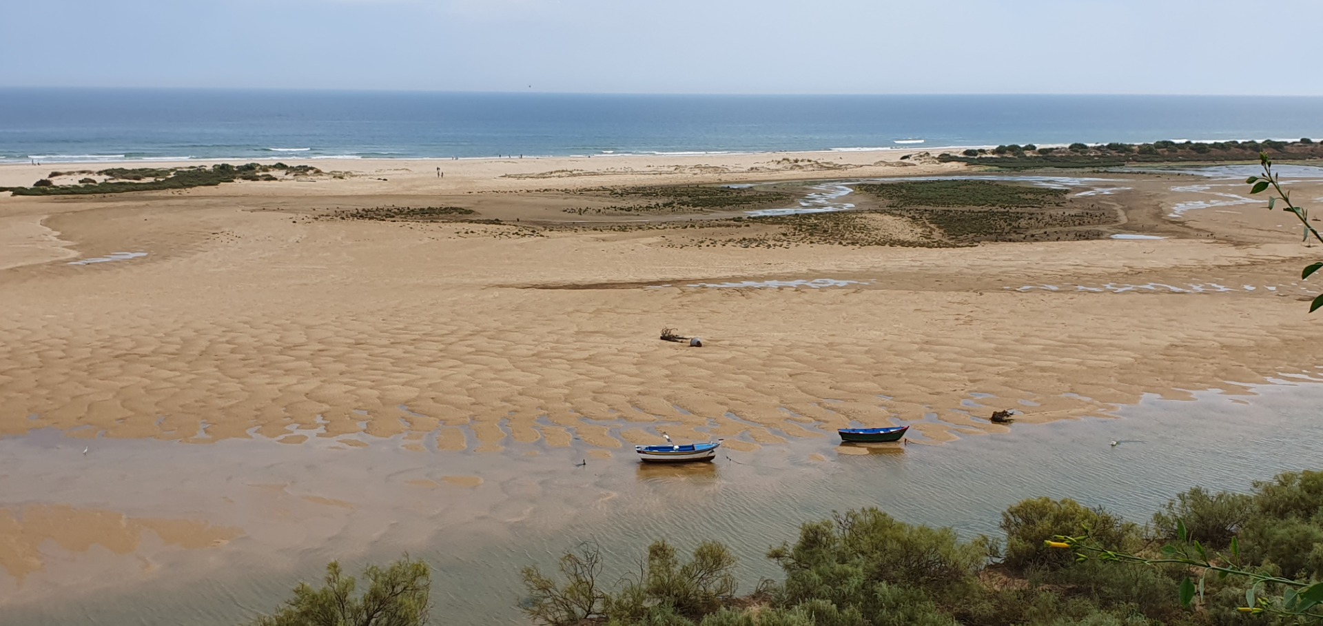 Weite Sandbucht von Cacela Velha - Algarve mit zwei blauen Booten im Wasser, Dünen, Küstenlinie und ruhigem Meer.